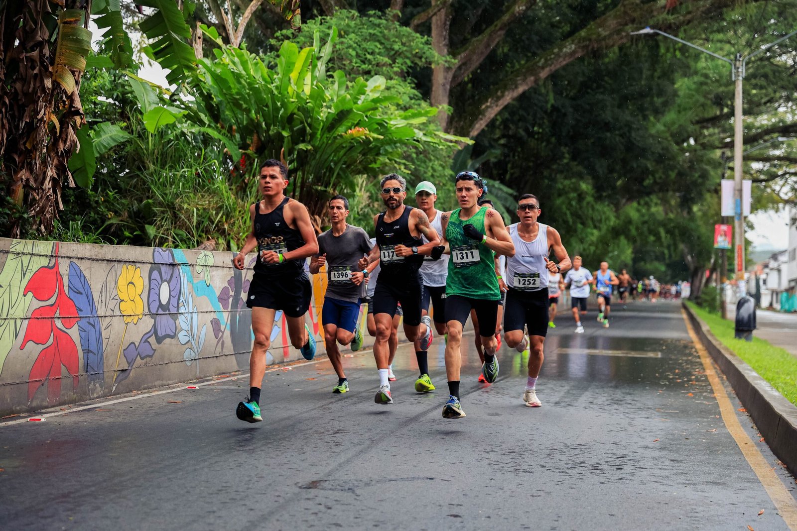 Athletes running in a vibrant road race in Risaralda, Colombia, surrounded by lush greenery.