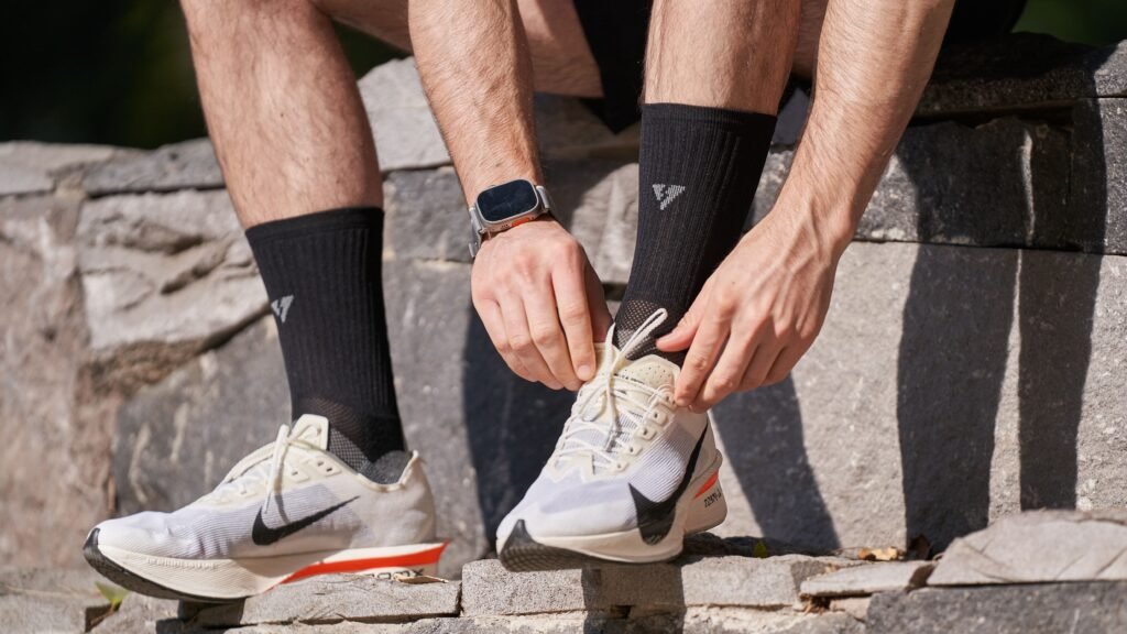 Close-up of a man tying his running shoes on stone steps, preparing for a run outdoors.