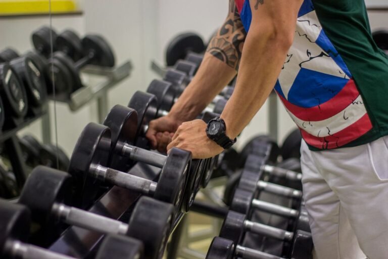 Man preparing to lift dumbbells in a gym, focusing on strength and fitness.